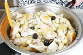 鶏肉を④のフライパンに入れ軽く炒めたら、ワインビネガー、白ワイン、水、ブラックオリーブ、蓮の実を入れます。煮立ったら、ローリエ、ローズマリーとホールトマトをくずし入れて煮込みます。